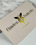 Beige product packaging with 'Flawless Butterfly' logo on a marble surface